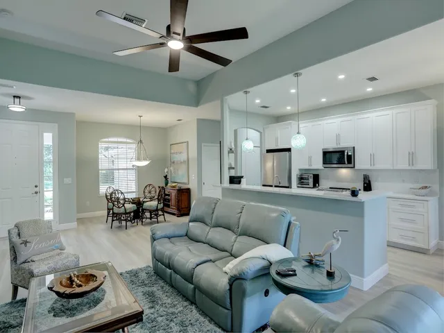 a living room with furniture kitchen view and a chandelier