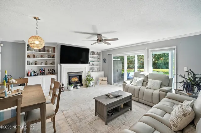 a view of a patio with couches chairs potted plants and floor to ceiling window with yard