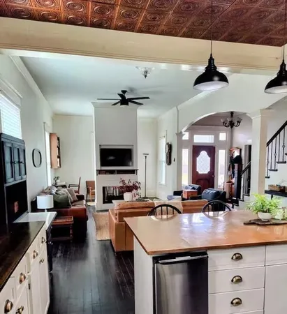 a living room with stainless steel appliances kitchen island a flat screen tv and a couch