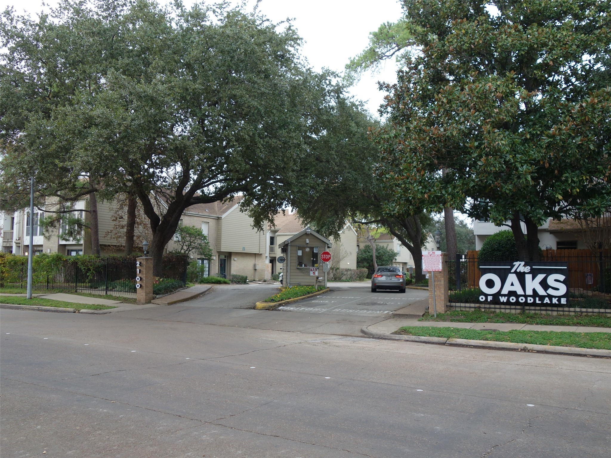 2100 Tanglewilde Street, Unit 373 Houston, TX 77063 - Photo 20 of 21 This photo shows the entrance to "The Oaks of Woodlake," a residential complex with mature trees providing shade and a welcoming atmosphere. The area is well-maintained, with a gated entrance and a 24 hour guard .