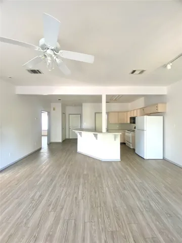 a view of a kitchen with wooden floor and a ceiling fan