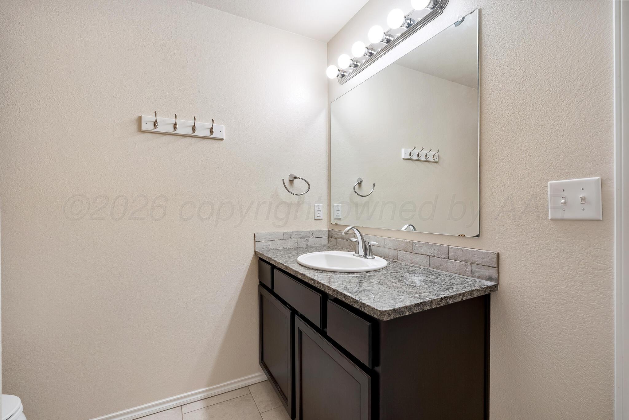 4807 Eberly Street Amarillo, TX 79118 - Photo 19 of 25 a bathroom with a granite countertop sink and a mirror