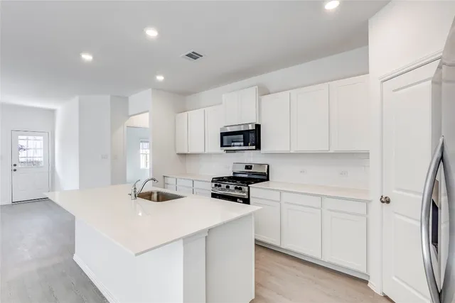 a kitchen that has a sink a microwave a refrigerator and cabinets