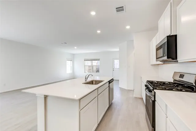 a view of kitchen with stainless steel appliances refrigerator stove microwave and cabinets