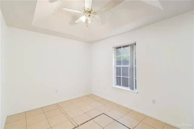an empty room with chandelier fan and windows