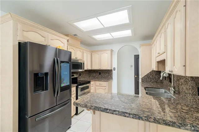 a kitchen with granite countertop a refrigerator stove and sink