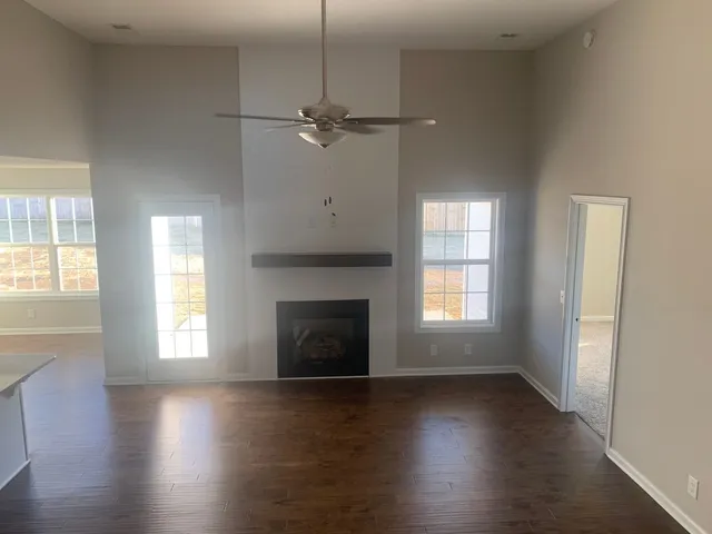 an empty room with wooden floor fireplace and windows