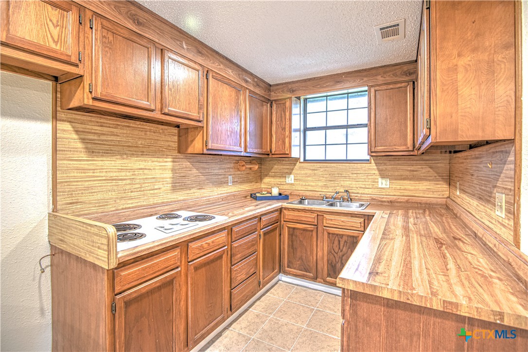 305 Tanglewood Road Temple, TX 76502 - Photo 40 of 46 a kitchen with stainless steel appliances granite countertop a stove a sink and a microwave