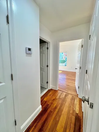 a view of a hallway with wooden floor and a bathroom