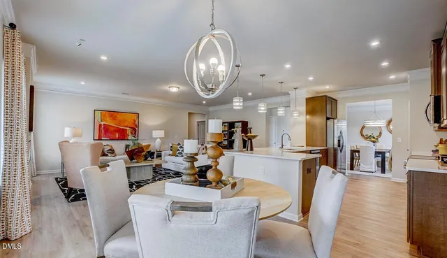 a living room with lots of furniture kitchen view and a chandelier