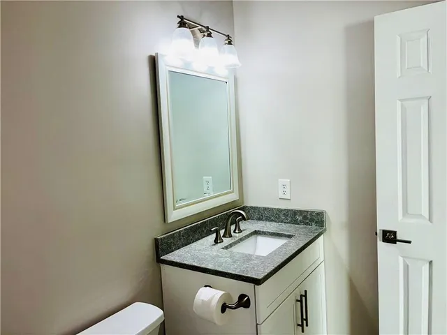 a bathroom with a granite countertop sink and a toilet