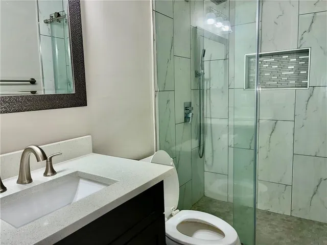 a bathroom with a sink a toilet and shower