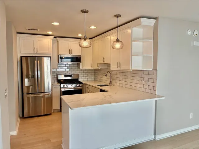 a kitchen with stainless steel appliances granite countertop a refrigerator a oven and white cabinets