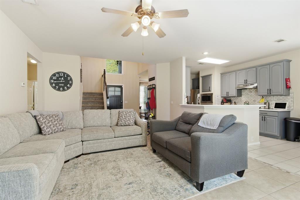 6625 Hayling Way Denton, TX 76210 - Photo 6 of 33 a living room with couches a fireplace and a kitchen view with wooden floor