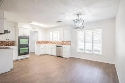 a kitchen with granite countertop white cabinets and stainless steel appliances