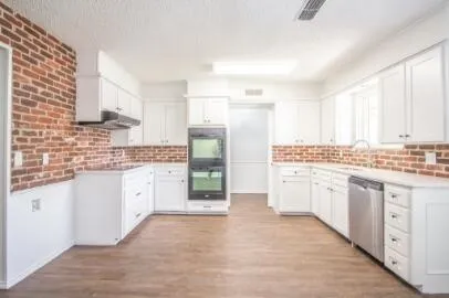 a kitchen with granite countertop a sink cabinets stainless steel appliances and a counter space