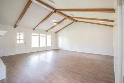 a view of an empty room with a window and wooden floor