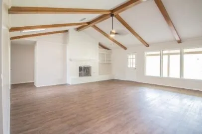 a view of an empty room with a window and wooden floor