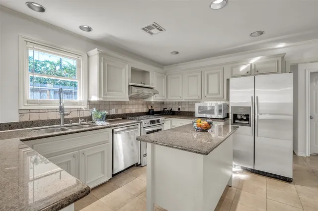 a kitchen with stainless steel appliances granite countertop a sink stove refrigerator and window