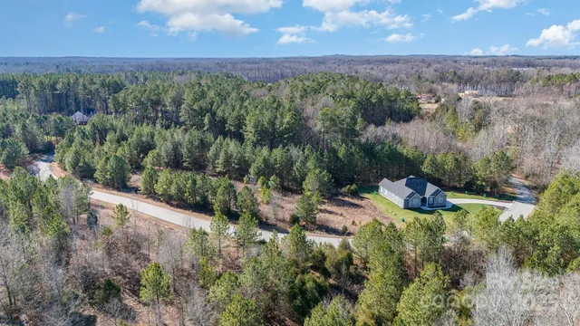 an aerial view of residential house with outdoor space and trees all around