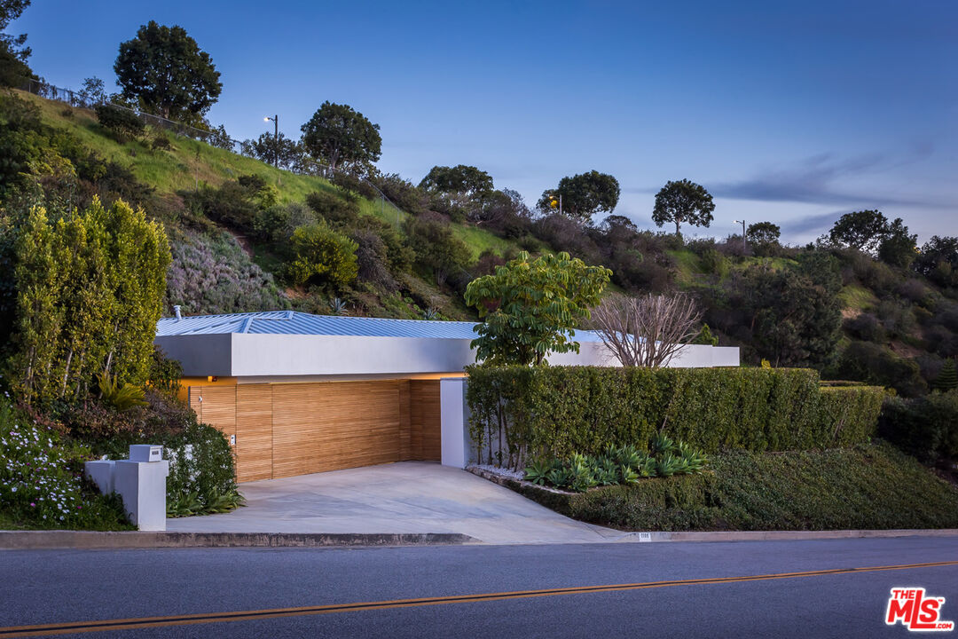 1106 North Hillcrest Road Beverly Hills, CA 90210 - Photo 12 of 54 a front view of a house with a yard and garage