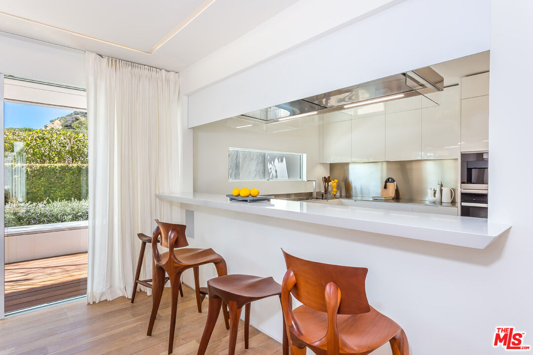 1106 North Hillcrest Road Beverly Hills, CA 90210 - Photo 19 of 54 a kitchen with a sink chairs and wooden floor