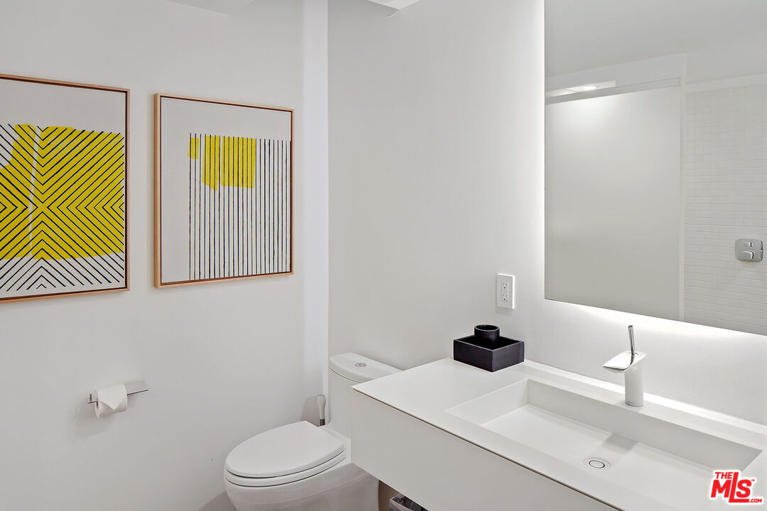 1106 North Hillcrest Road Beverly Hills, CA 90210 - Photo 35 of 54 a bathroom with a sink a toilet and a mirror