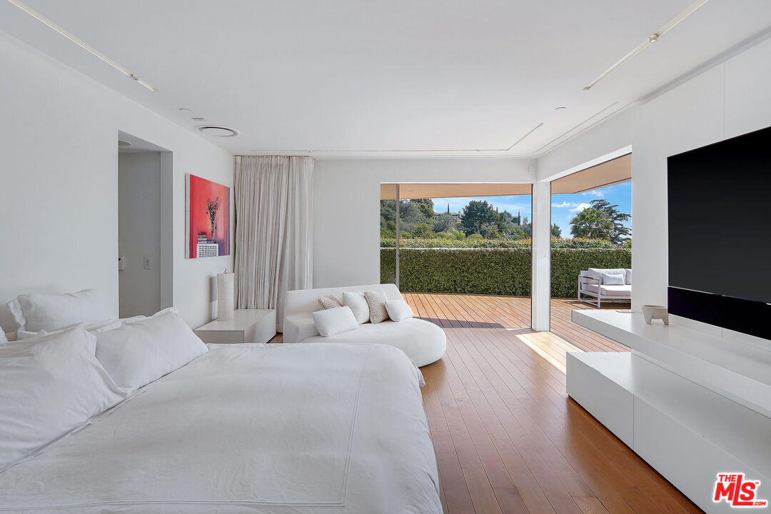 1106 North Hillcrest Road Beverly Hills, CA 90210 - Photo 8 of 54 a bedroom with a large bed and a flat tv screen next to a window