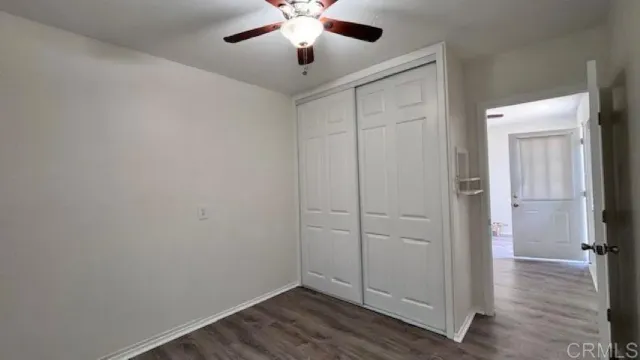 an empty room with wooden floor closet and ceiling fan