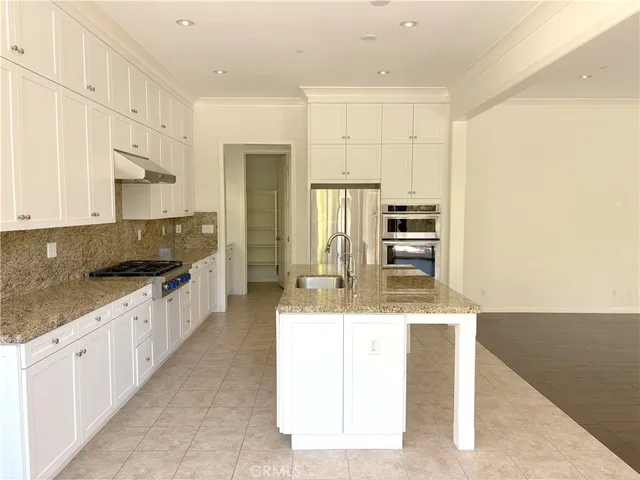 a large kitchen with granite countertop a sink a stove and cabinets