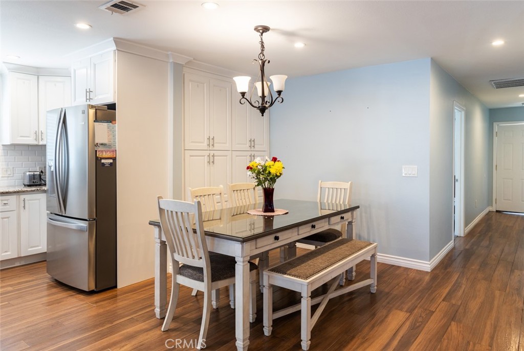 5512 Marcella Avenue Cypress, CA 90630 - Photo 15 of 39 a dining room with wooden floor a chandelier a wooden table and chairs