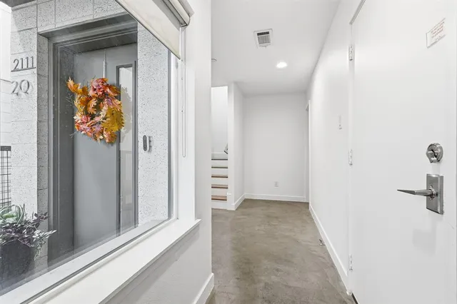a view of empty room with wooden floor and kitchen