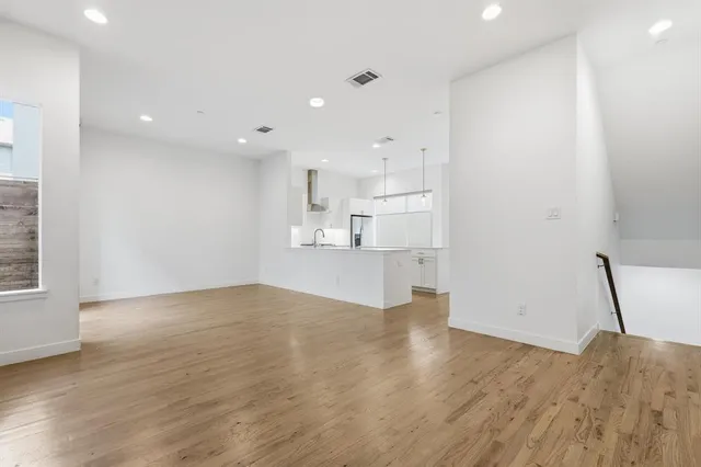 a kitchen with stainless steel appliances granite countertop a sink a stove a refrigerator and island with wooden floor