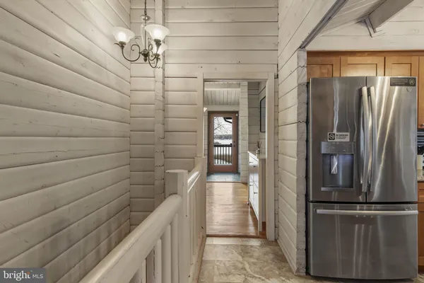 a view of a refrigerator in kitchen and an empty room