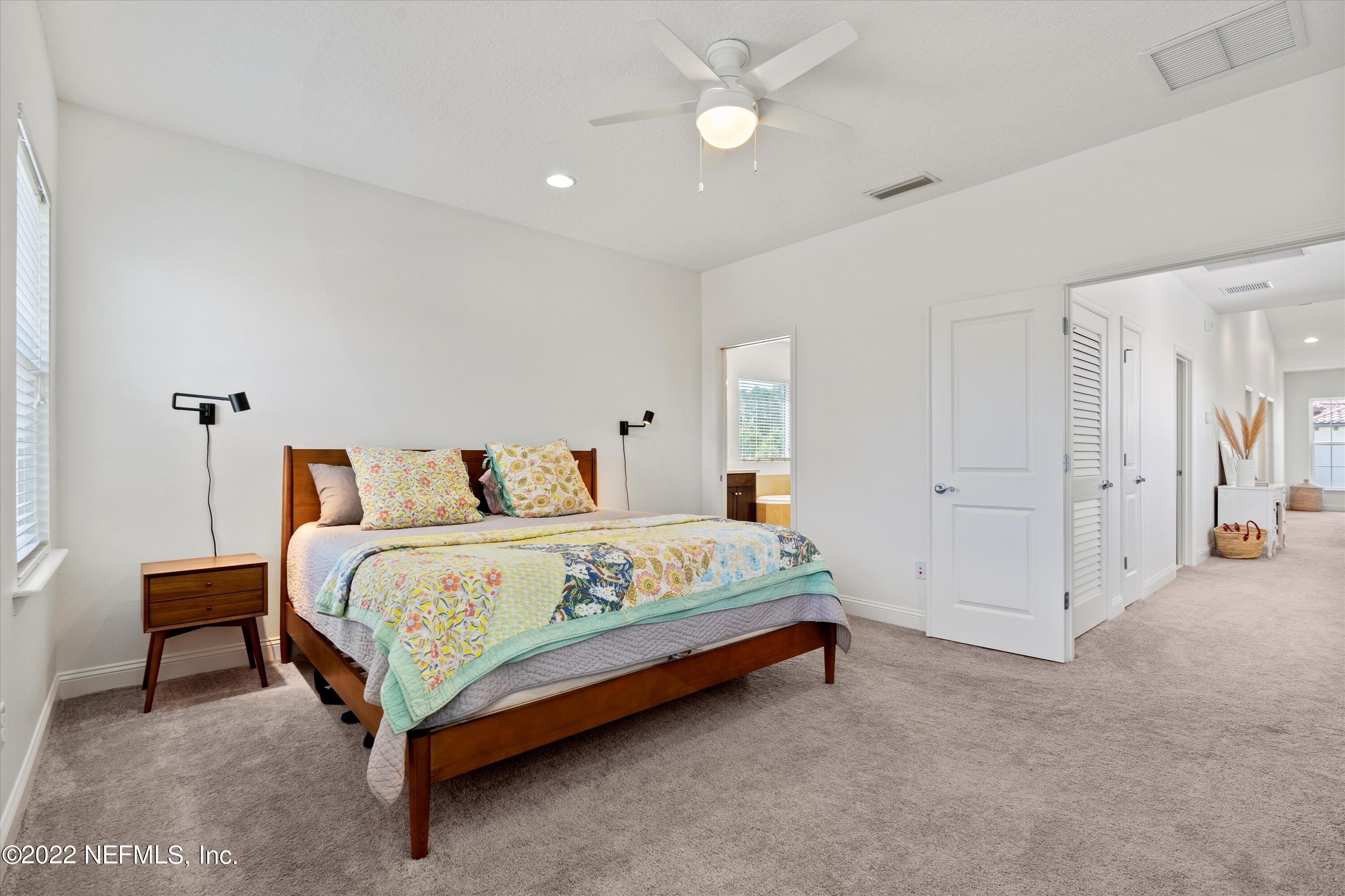 245 Rialto Drive Ponte Vedra, FL 32081 - Photo 19 of 29 a spacious bedroom with a bed and a chandelier
