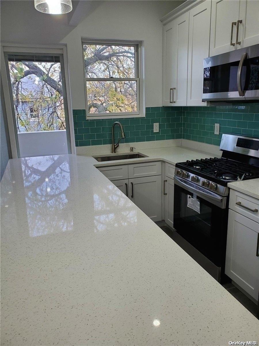 3043 Fulton Street Brooklyn, NY 11208 - Photo 13 of 14 a kitchen with stainless steel appliances granite countertop a stove a sink and a microwave