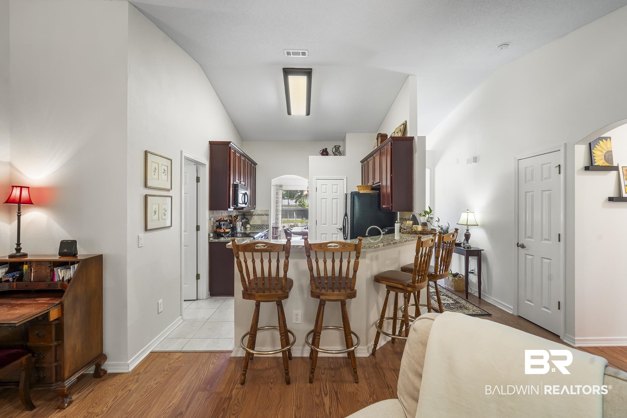 1802 South Bay Street Foley, AL 36535 - Photo 11 of 30 Kitchen with arched walkways, freestanding refrigerator, a peninsula, a kitchen bar, and light stone counters