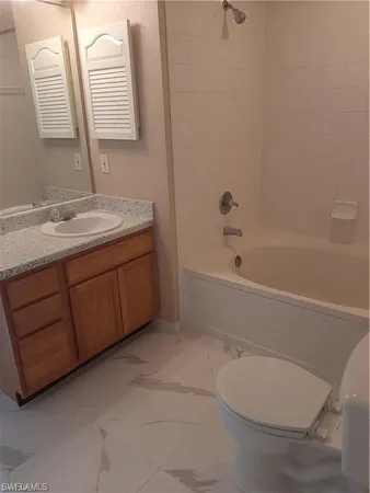 a bathroom with a granite countertop sink a toilet and bathtub