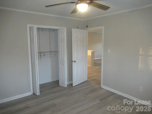 an empty room with wooden floor and a ceiling fan