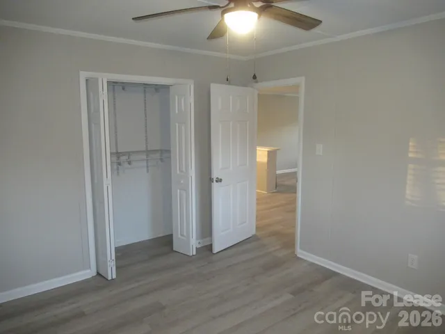 an empty room with wooden floor and a ceiling fan