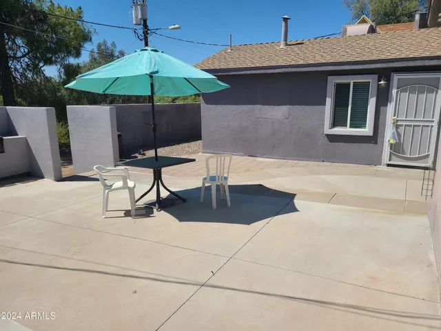 a patio with a table and chairs under an umbrella