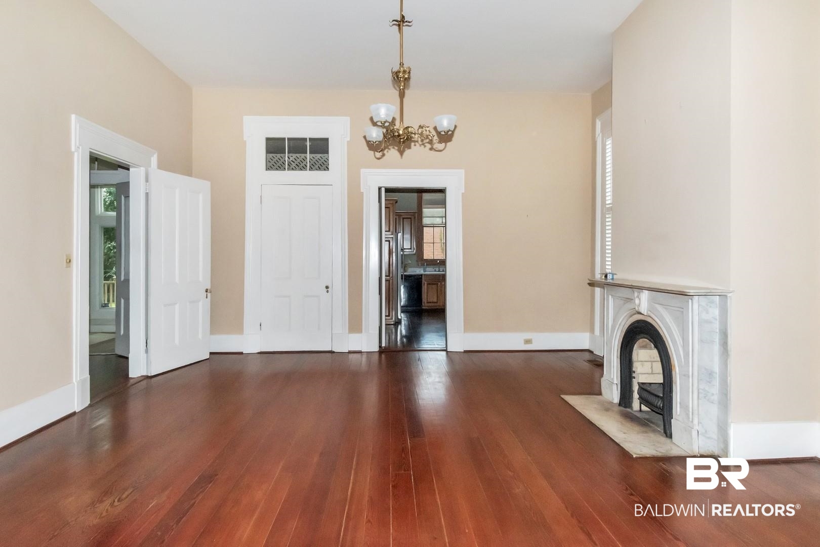 959 Dauphin Street Mobile, AL 36604 - Photo 6 of 43 Unfurnished living room with a high end fireplace, an inviting chandelier, and hardwood / wood-style floors