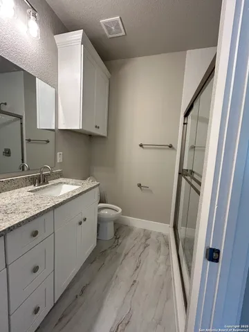 a bathroom with a granite countertop sink toilet and shower