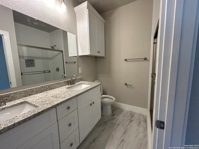 a bathroom with a granite countertop sink toilet and mirror