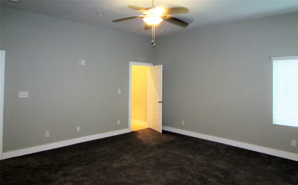 an empty room with a chandelier fan and windows