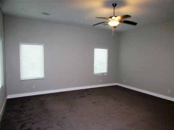 an empty room with windows and chandelier fan