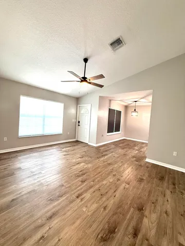 a view of empty room with wooden floor and fan