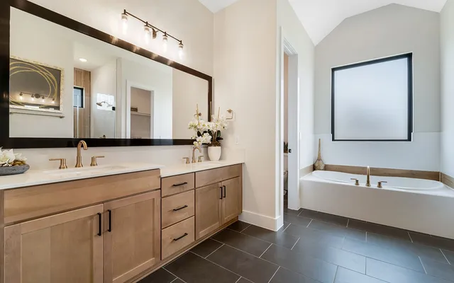 a spacious bathroom with a double vanity sink mirror and bathtub