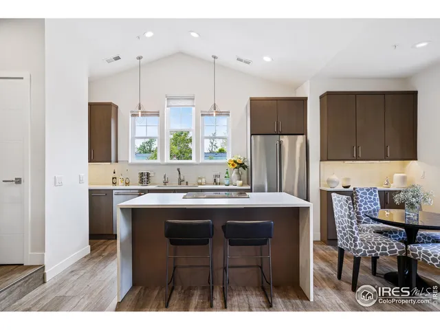 a kitchen with stainless steel appliances a table chairs refrigerator and sink