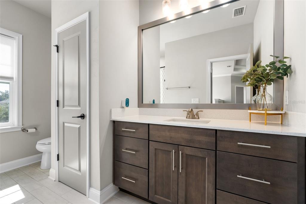 3474 Southwest 109 Drive Gainesville, FL 32608 - Photo 44 of 60 a bathroom with a granite countertop sink a toilet and a mirror